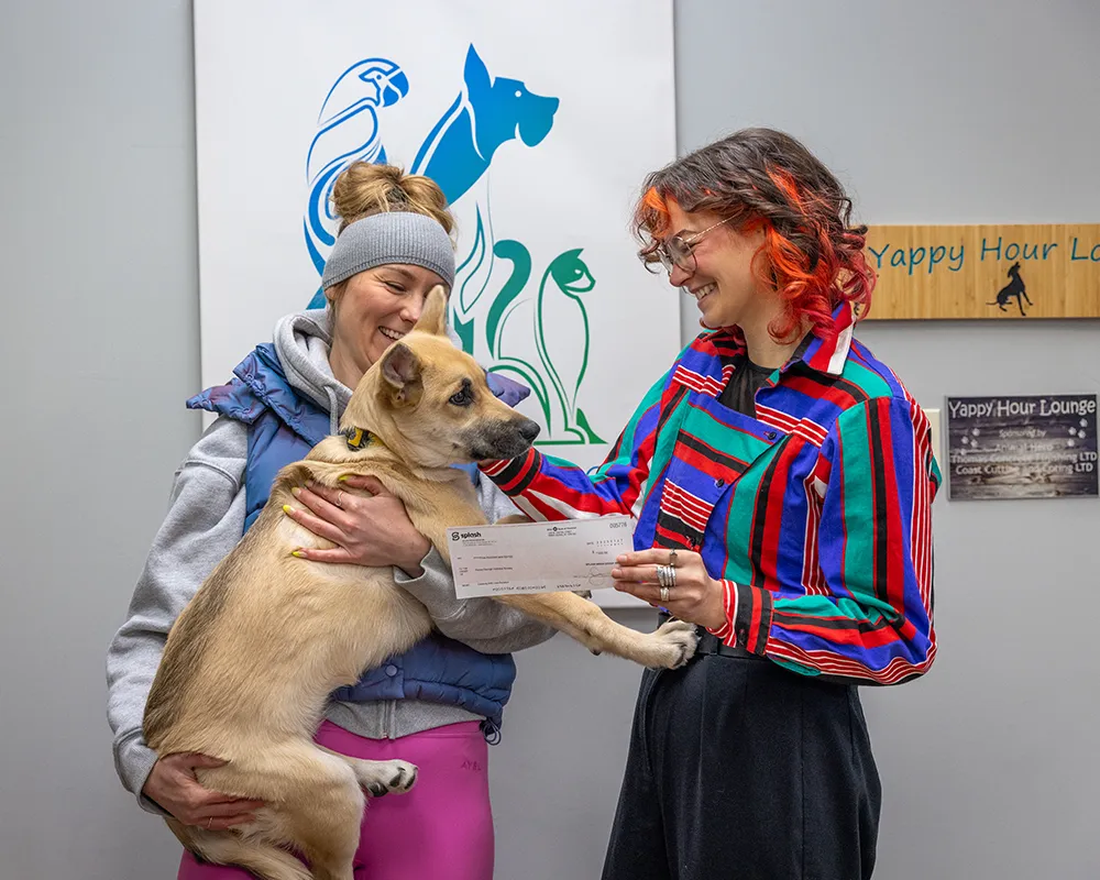 Timea passing check along to Humane Society volunteer with puppy